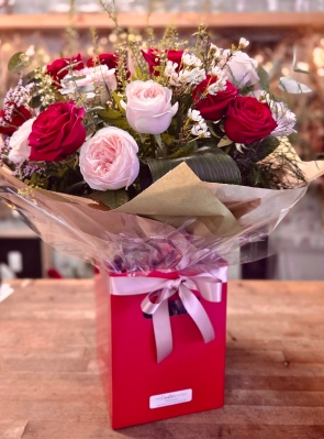 12 stunning roses in mixed colours of red and pink with pretty wax flower presented in a gift box in water with a satin bow.
