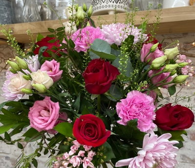 Red and pink hand tied bouquet presented in a gift box in water.