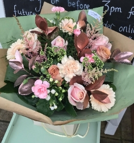 Rose gold and peach tones, hand tied bouquet presented in a gift box in water.