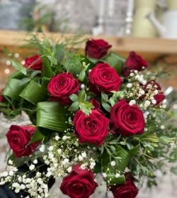 12 high quality red roses with gypsophila, hand tied and presented in a gift box in water.