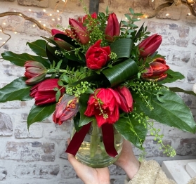Two dozen hand tied red tulips in an included eco recycled glass vase.