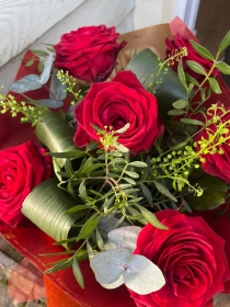 6 luxury red roses presented in a red gift box in water with a red satin bow.