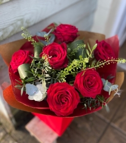 6 luxury red roses presented in a red gift box in water with a red satin bow.