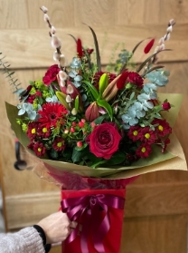 Festive reds mixed flowers large bouquet presented in a gift box in water.