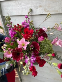 Red and pink florists choice bouquet simply wrapped in paper with a satin bow.