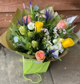 Spring colours hand tied bouquet presented in a gift box in water.